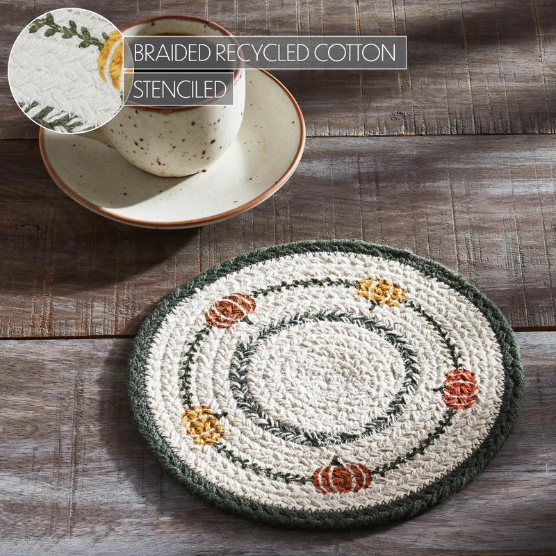 Round braided recycled cotton trivet with stenciled design on a wooden surface