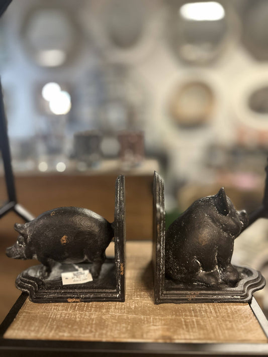 Pair of pig-shaped bookends on a wooden surface with a blurred background