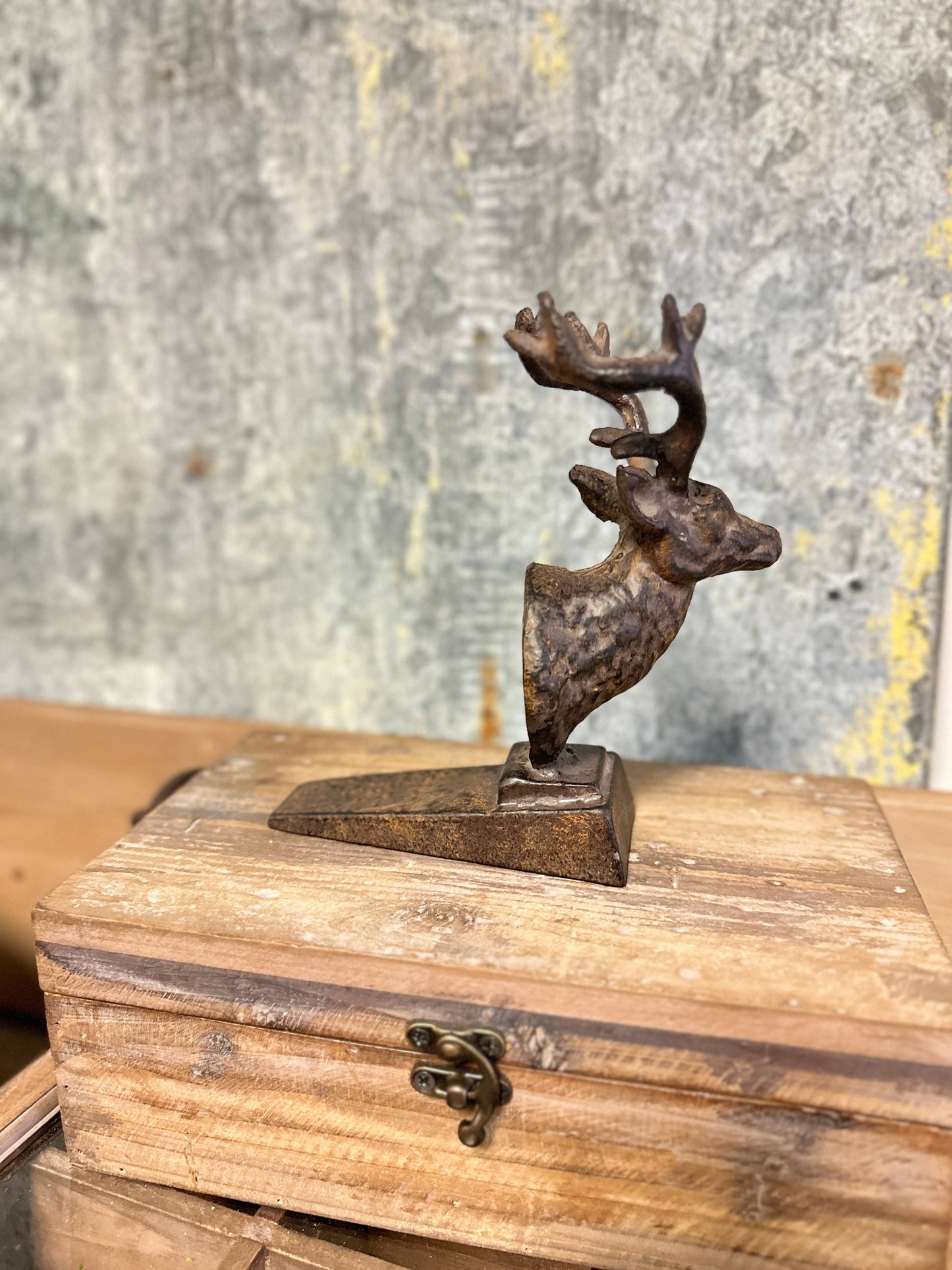 Decorative deer figurine on top of a wooden box with a rustic background