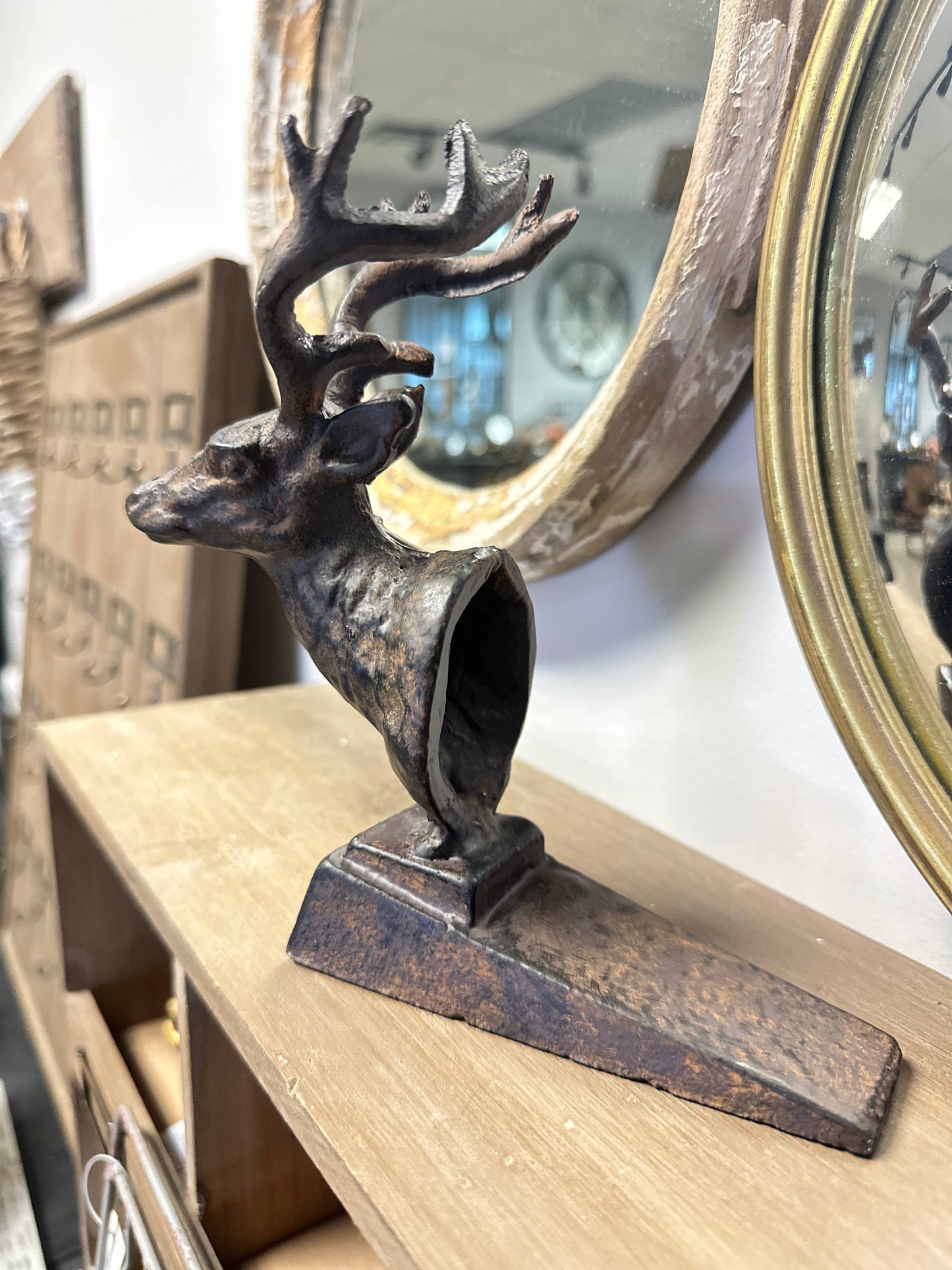 Decorative metal deer sculpture on a wooden surface with a mirror in the background