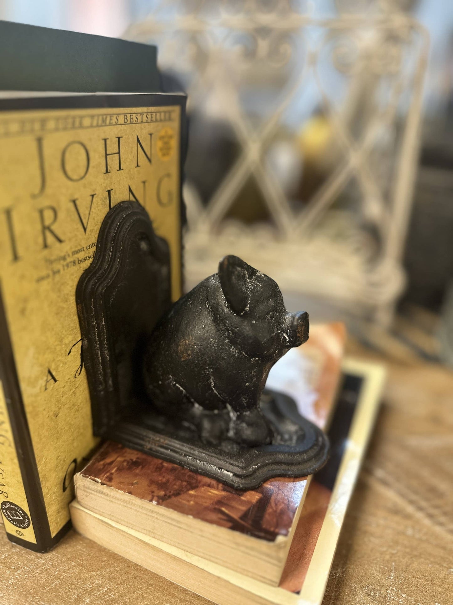 Black pig-shaped bookend on a stack of books with a blurred background