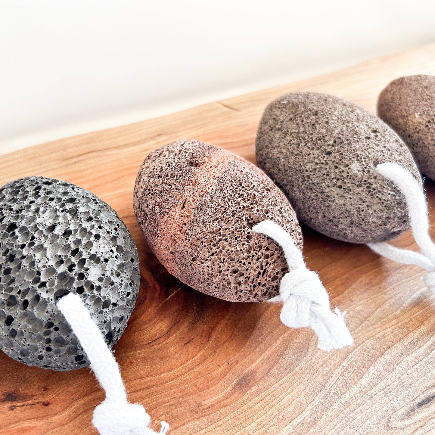 Four textured stones with white strings on a wooden surface