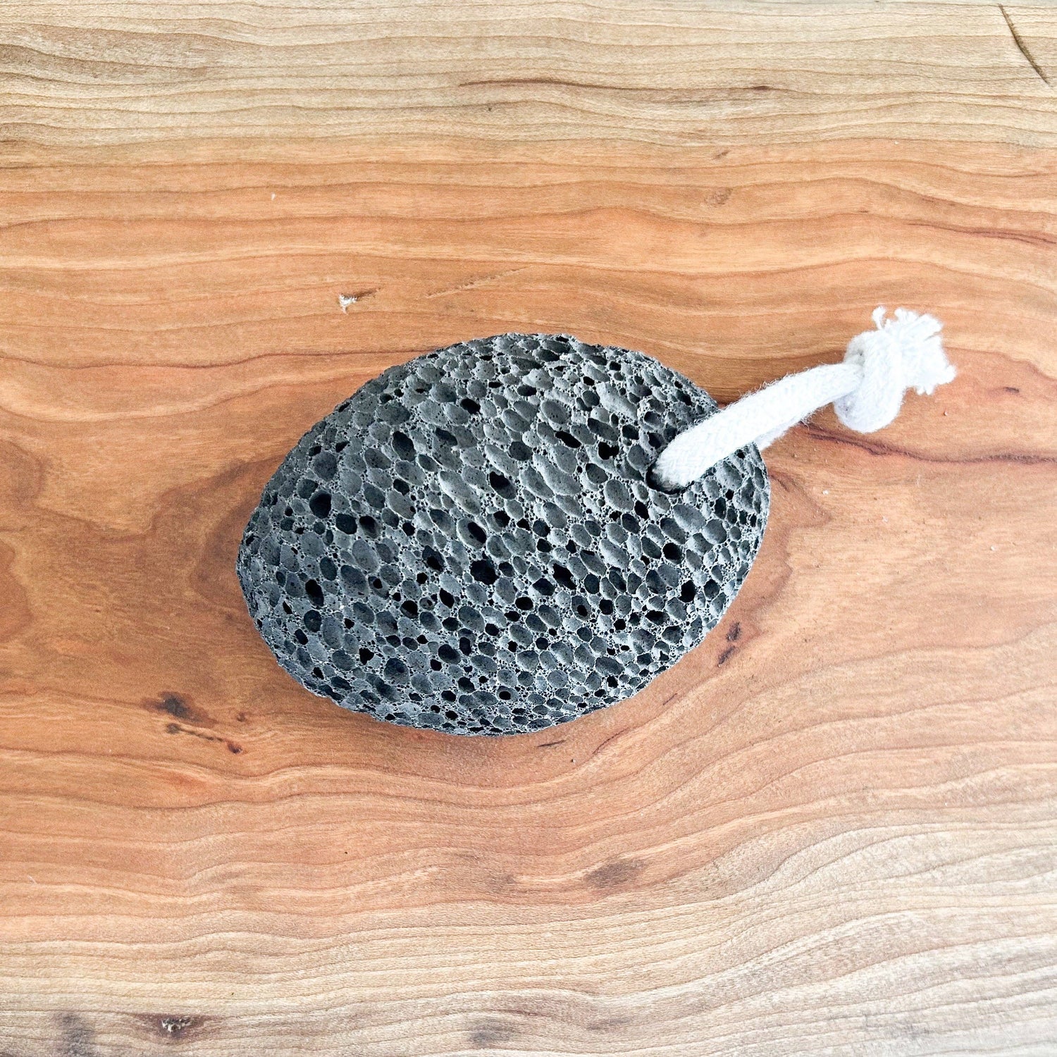 Pumice stone with a rope handle on a wooden surface