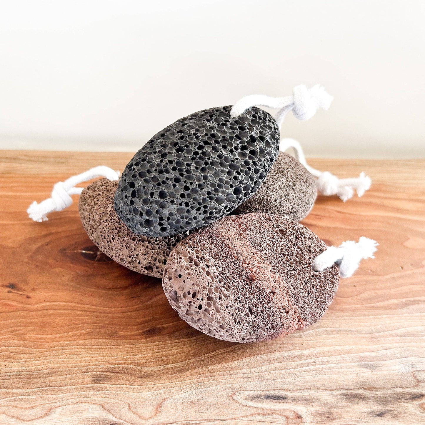 Three textured stones with white strings on a wooden surface