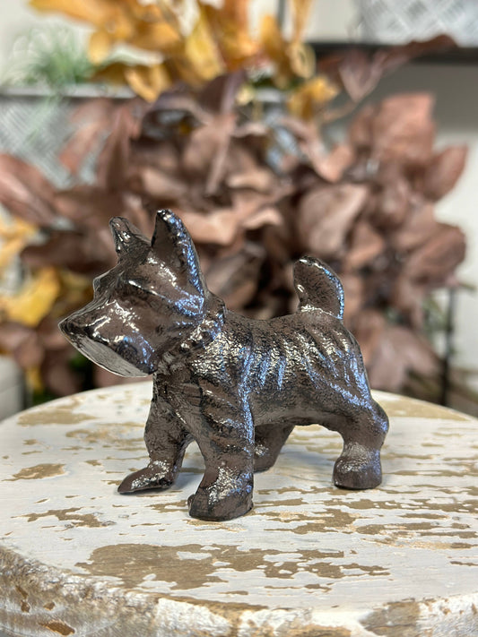Bronze dog figurine on a textured surface with blurred background