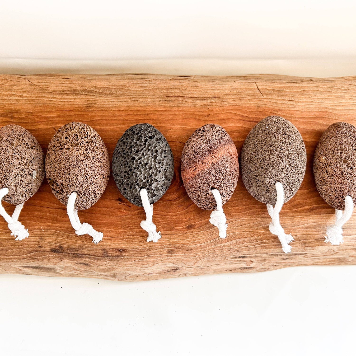 Row of pumice stones with white strings on a wooden board