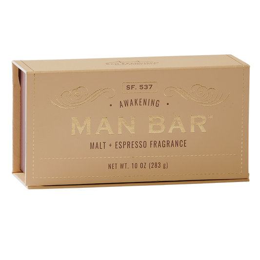 A beige bar of soap packaged in a box with 'MAN BAR' written on it, along with the scent description 'Malt + Espresso Fragrance' and net weight indication '10 oz (283 g)'.