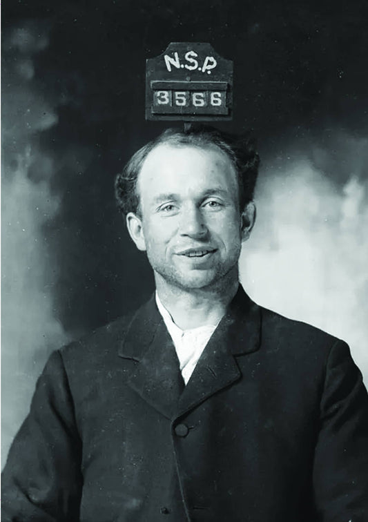 Black and white mugshot of a man with a 'N.S.P.' label on his head