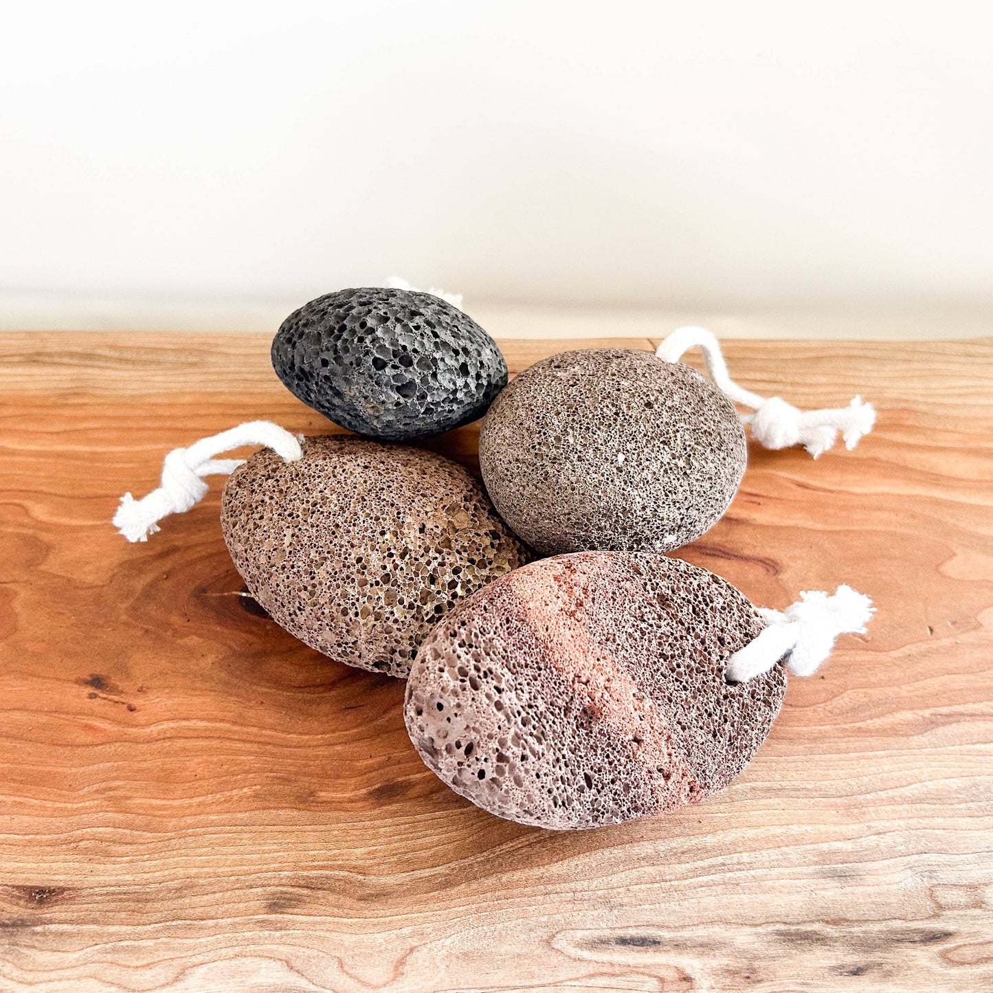 Four textured stones with strings on a wooden surface