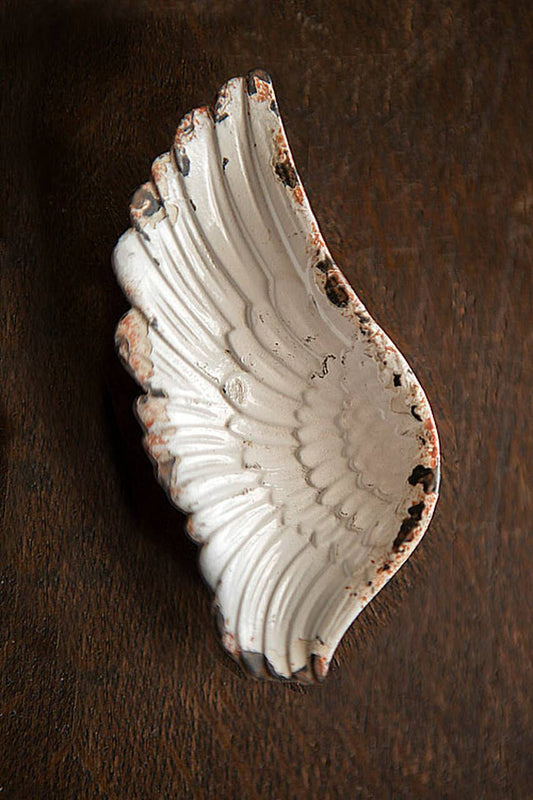 Decorative ceramic wing-shaped dish on a wooden surface